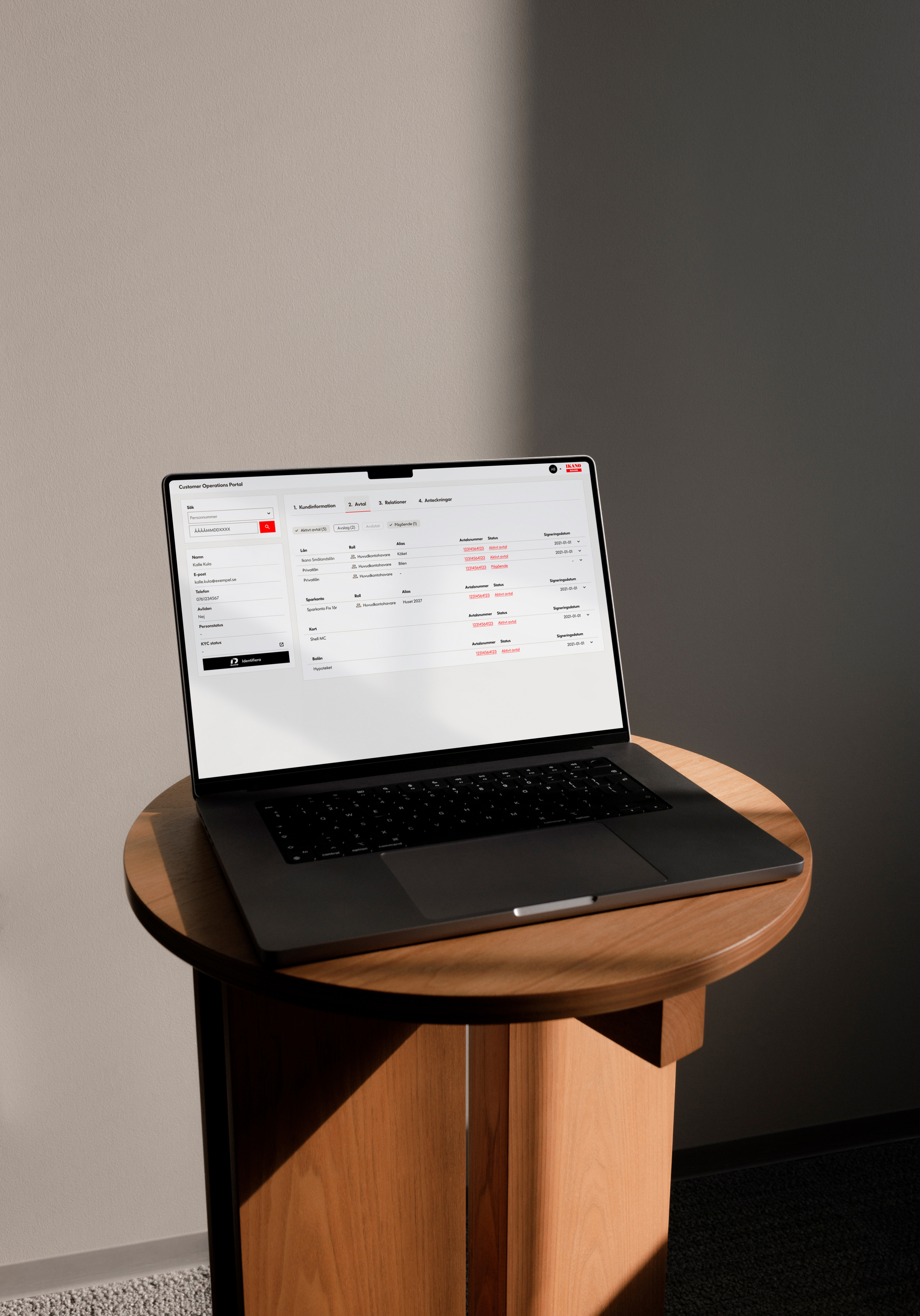 Macbook displaying a design, placed on a wooden table with beige curtains in the background.