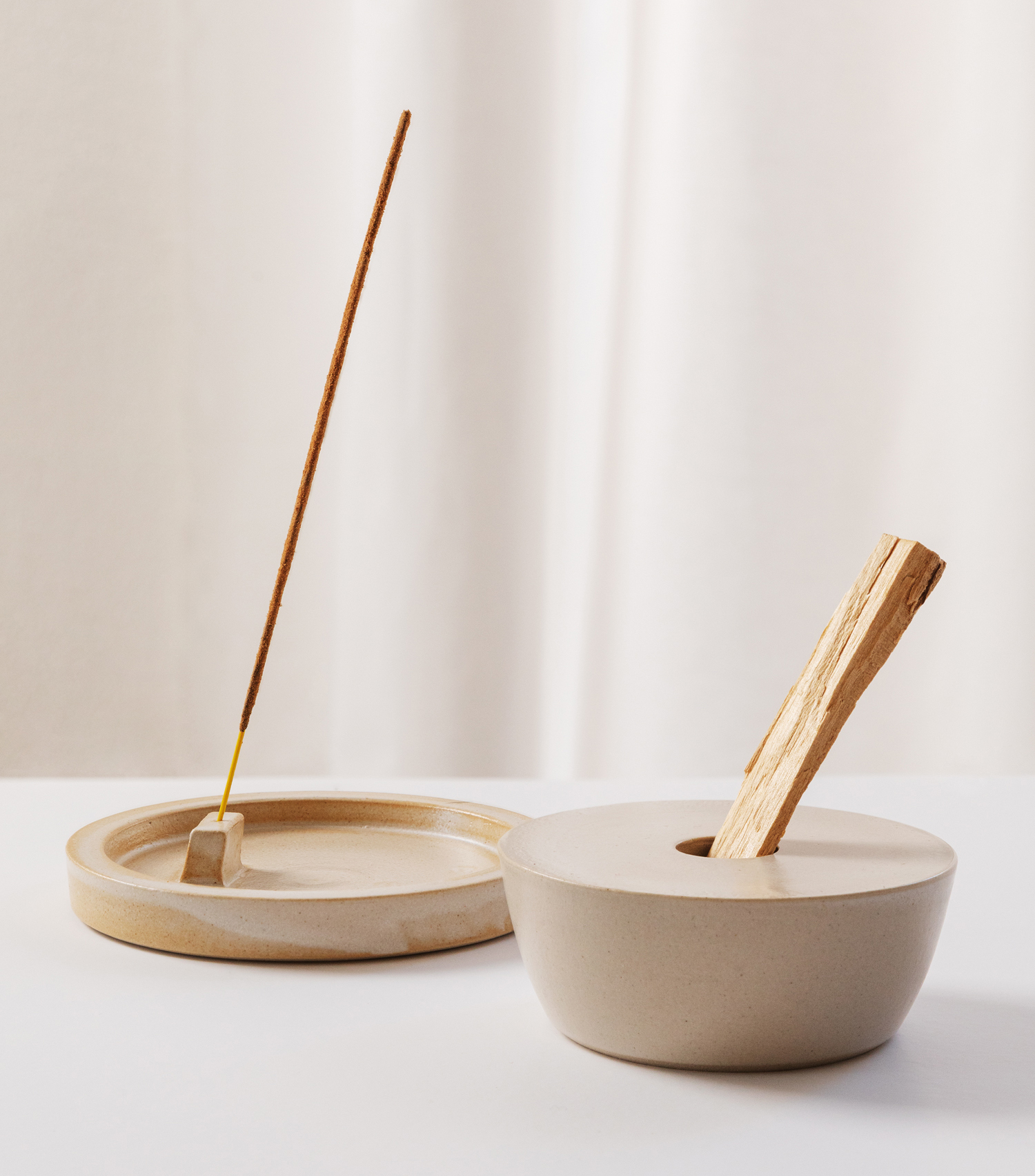 Ceramic incense holders for sticks and palo santo wood, styled in a studio with a flowy white backdrop.