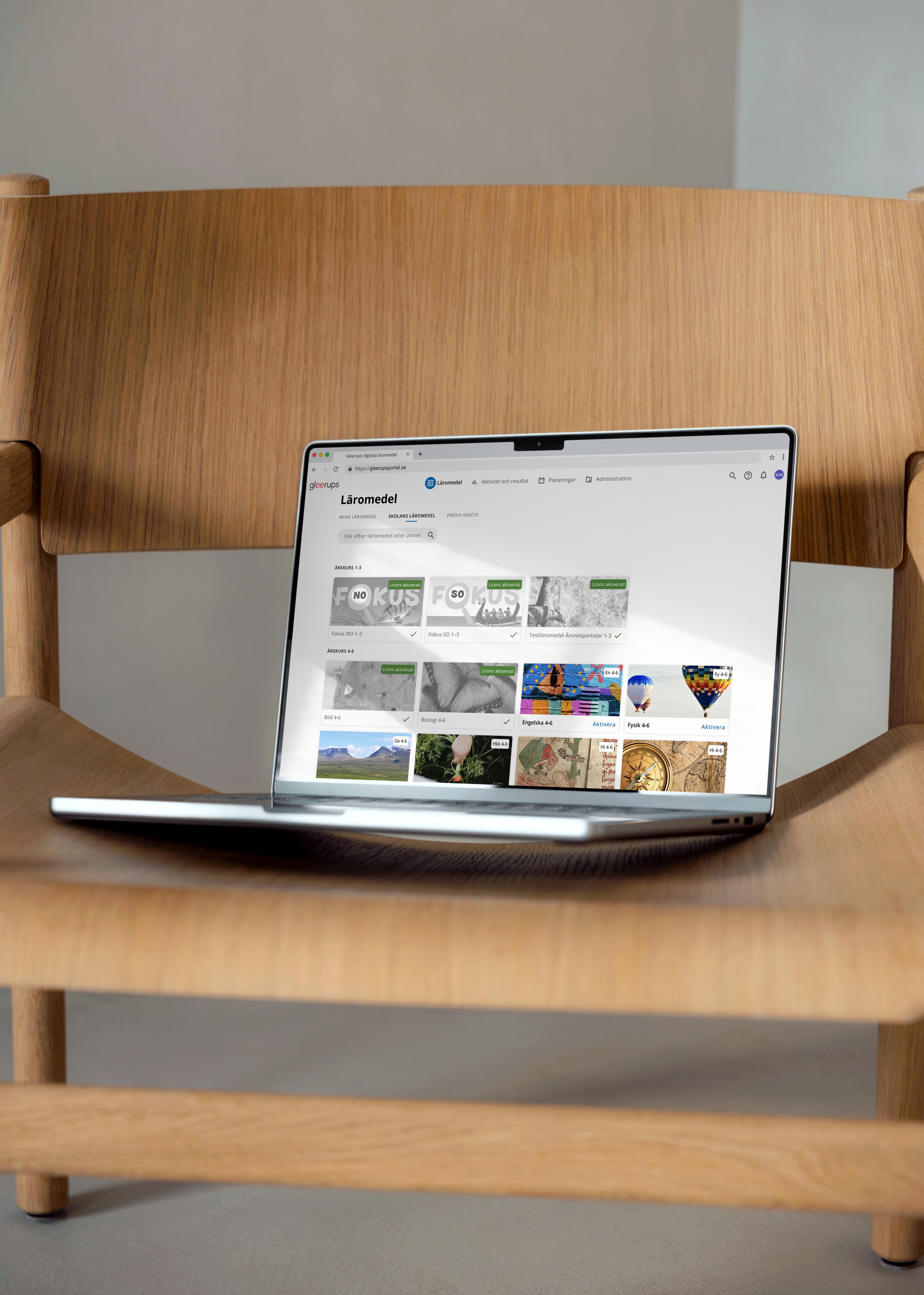 MacBook showing a design, placed on a wooden chair.